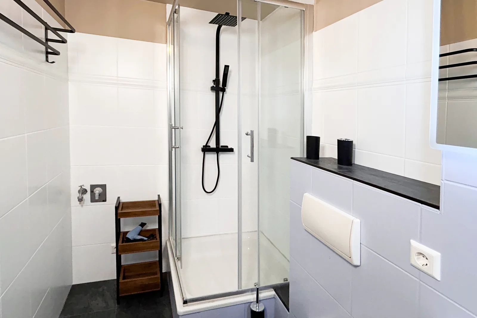 Glasdusche mit schwarzen Armaturen und weißen Wandfliesen