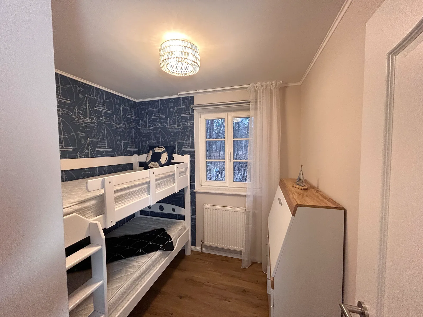 Kinderzimmer mit weißem Etagenbett und maritimer Tapete