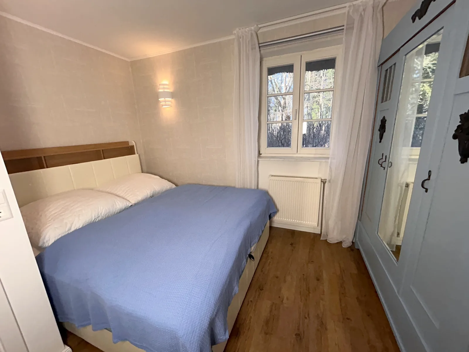 Doppelbett mit blauer Tagesdecke und Kleiderschrank im Schlafzimmer