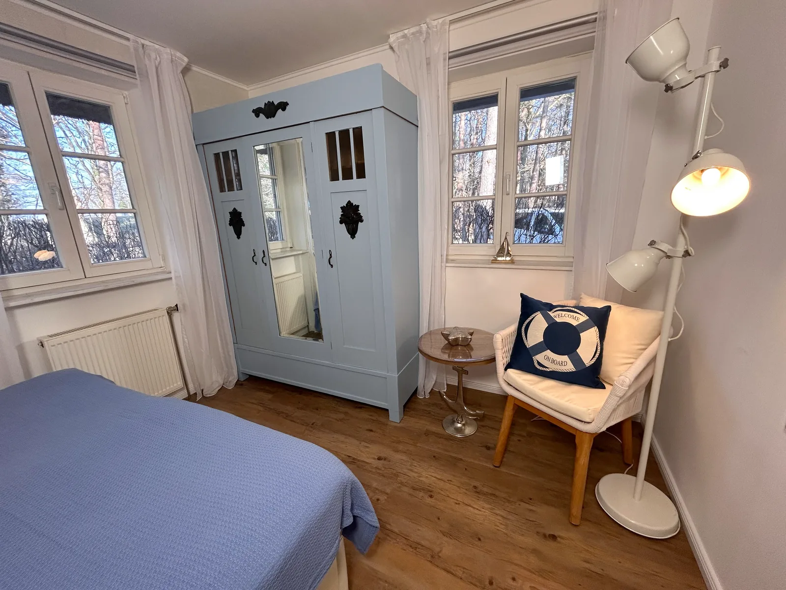 Schlafzimmer mit blauem Kleiderschrank und Lesesessel am Fenster