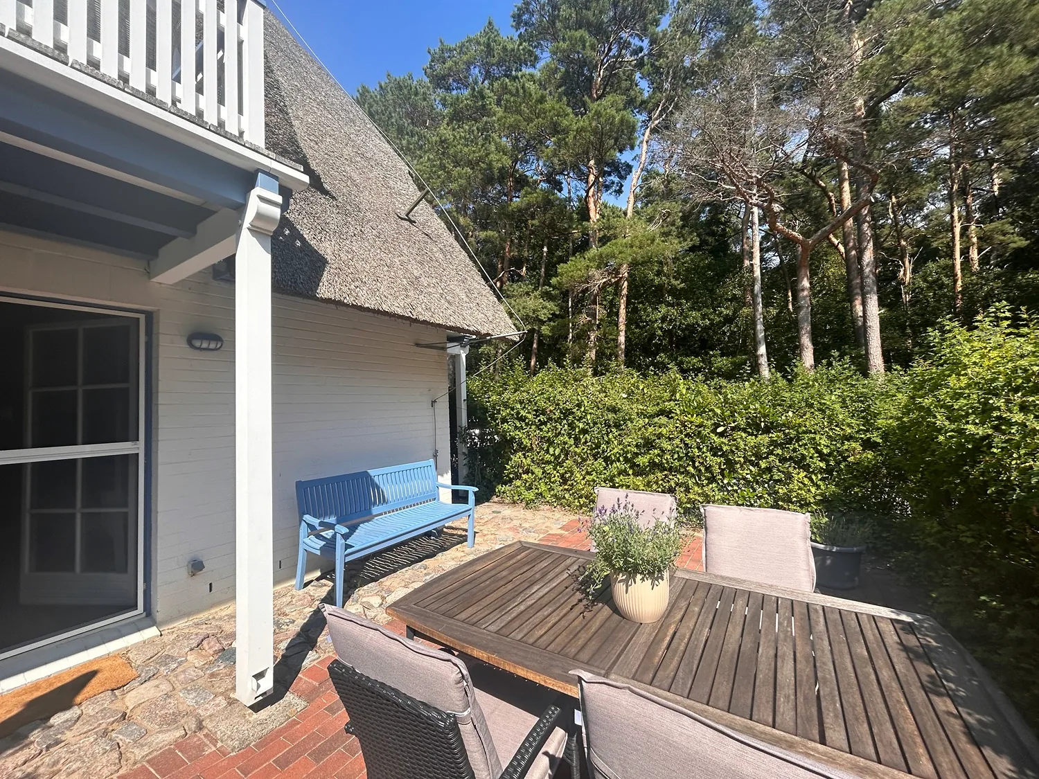 Terrassentisch und blaue Bank an der Hauswand